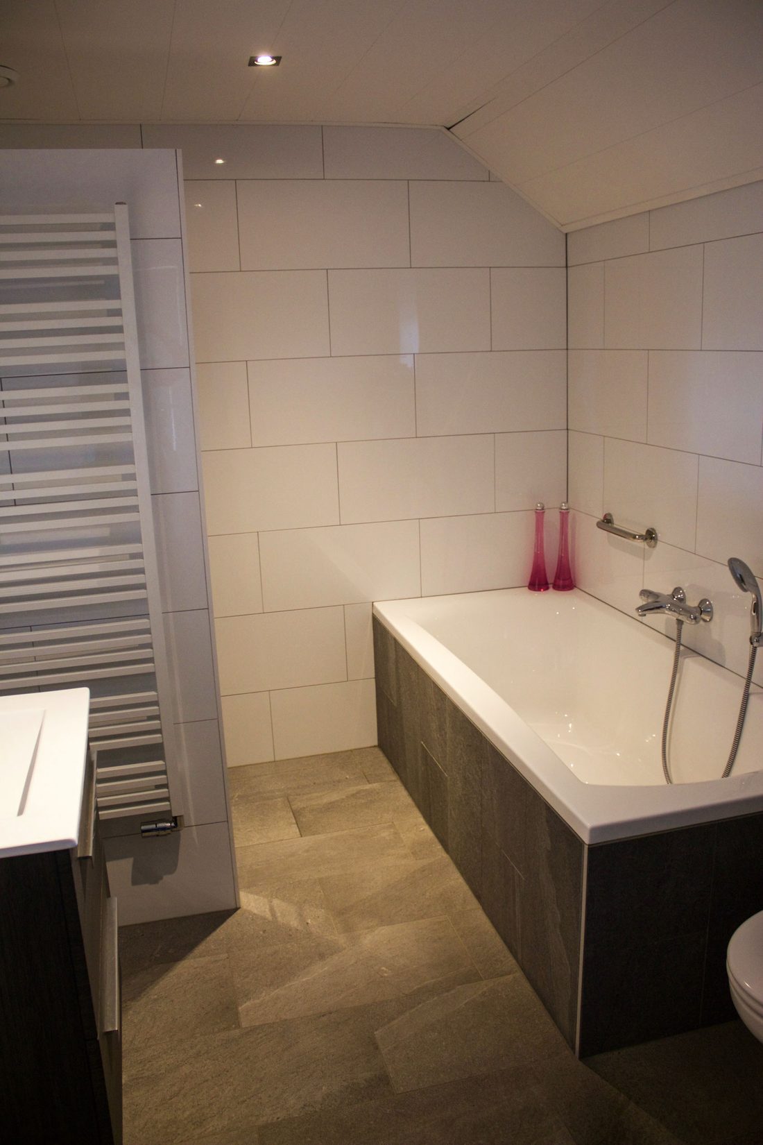 Gerenoveerde badkamer met ligbad, natuursteenvloer en wandtegels